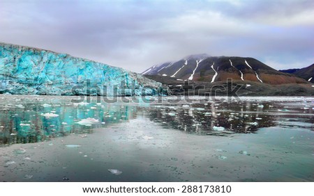 Beautiful scenery - blue ice of Esmark glacier and black mountain reflected at calm water of  Istfjorden - view from cruise ship, Spitsbergen archipelago (Svalbard island), Norway, Greenland Sea