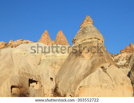 Beautiful barren landscape - ashen mountains (volcanic rock) - eerie carved structures against the background of blue sky at the evening in Red Valley, Goreme, Cappadocia, Central Anatolia, Turkey