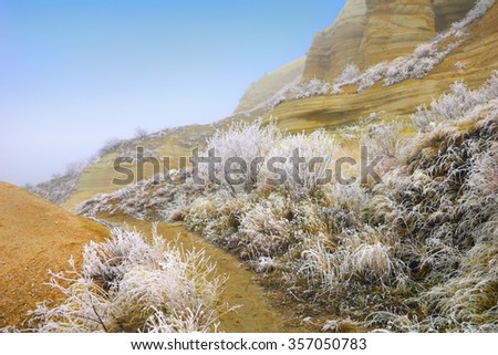 Country path against the background of incredible barren landscape with ashen mountains and trees covered with hoar-frost in Love Valley Goreme, Cappadocia, Central Anatolia, Turkey