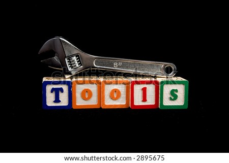 adjustable wrench resting on wooden blocks spelling out wrench