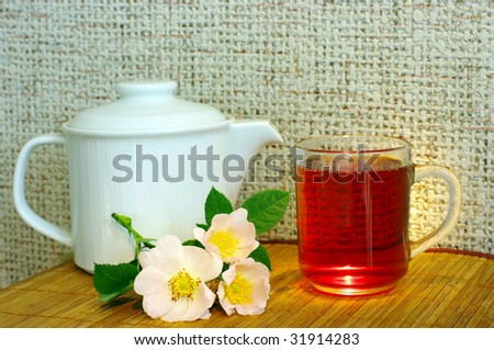 tea with dog-rose flowers and white teapot