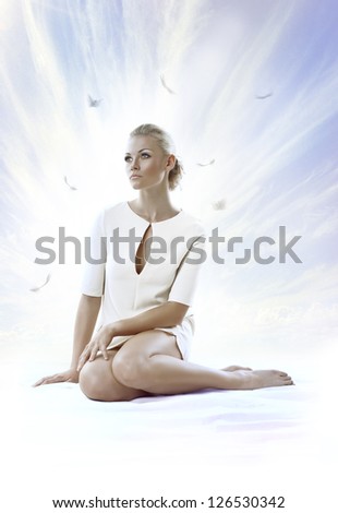 pretty blonde girl with elegant dress sitting on white floor, with a sky as a background , she face is turned at right and she looks in front of her