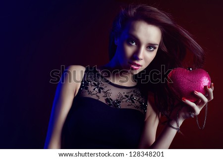 Beautiful woman partying wearing black dress and heart shaped purse