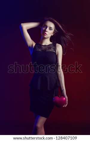 Beautiful woman partying wearing black dress and heart shaped purse