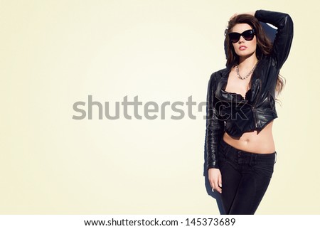 Glamorous young woman in black leather jacket and sunglasses on the white background
