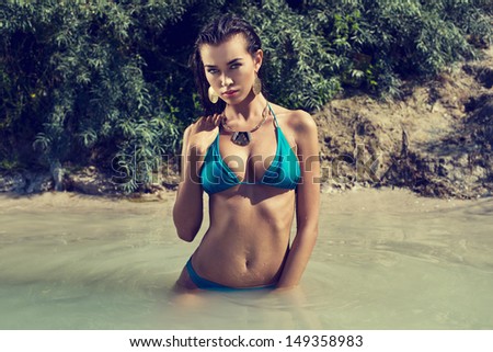 Beautiful long hair female model wearing bikini, posing in the water, outdoor portrait