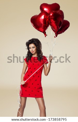 Beautiful brunette young woman in red dress with a heart-shaped balloons. Valentine\'s day