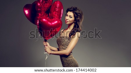 Beautiful brunette young woman in golden dress with a heart-shaped balloons. Valentine's day