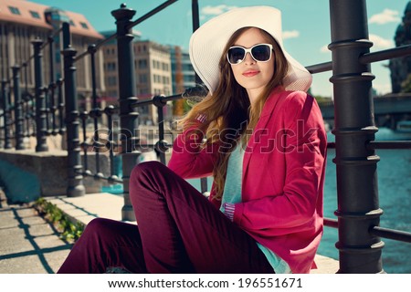 Fashion young woman wearing summer hat and sunglasses at riverside