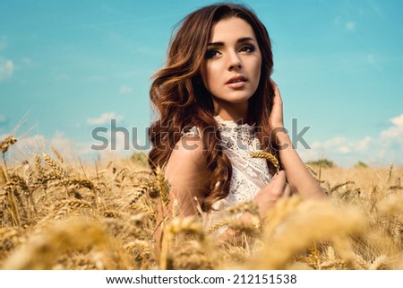 Beautiful woman in rye field wearing white dress. Rural lifestyle
