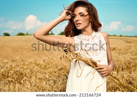 Beautiful woman in rye field wearing white dress. Rural lifestyle