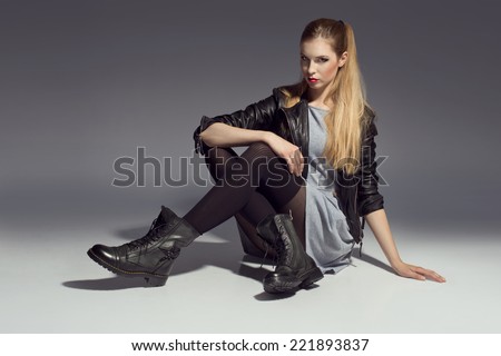 young woman posing in dress and leather jacket and grunge boots