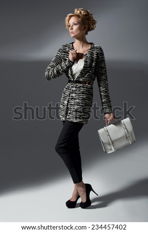 Beautiful elegant woman in stylish cardigan, high heels holding handbag. Fashion shot