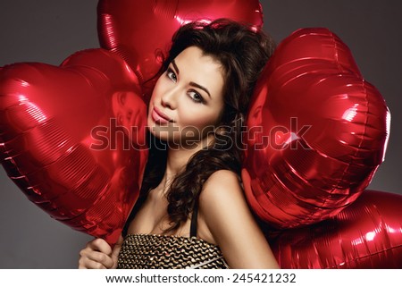 sexy brunette young woman in golden dress with a heart-shaped balloons. Valentine's day
