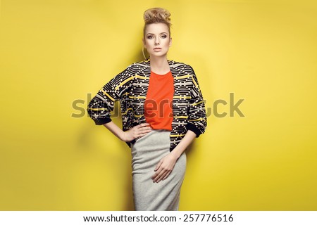 Fashion model in nice clothes posing in the studio on yellow background