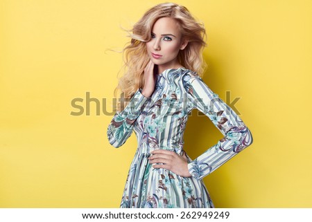 beautiful young blonde woman in nice spring dress, posing on yellow background in studio. Fashion photo