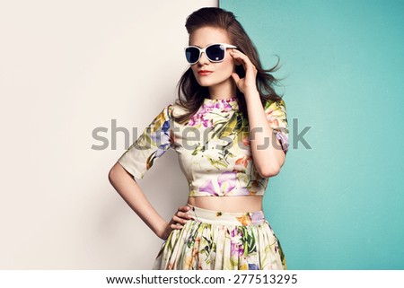 beautiful young woman in nice spring dress  with flower pattern, sunglasses, posing on yellow background in studio. Fashion photo