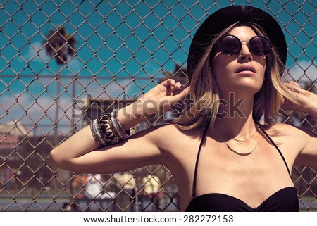 Pretty hipster girl in sunglasses, jeans shorts, black bikini and a hat. Close-up lifestyle outdoor portrait
