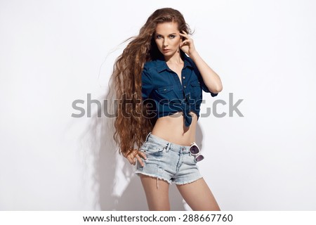 Beautiful young woman in jeans shirt and shorts. Summer fashion photo. Long healthy hair
