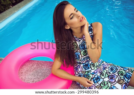 fashion photo of sexy beautiful girl with brunette in nice clothes relaxing beside a swimming pool
