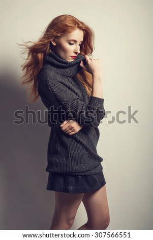 Beautiful young red haired woman with nice make up in autumn color, red lips, turtleneck. Fashion studio photo