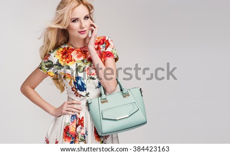beautiful young blonde woman in nice spring dress, handbag posing in a studio. Fashion spring summer photo