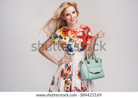 beautiful young blonde woman in nice spring dress, handbag posing in a studio. Fashion spring summer photo