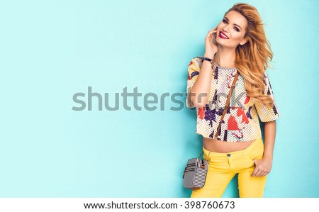 Beautiful woman wearing nice clothes, handbag posing on turquoise background. Fashion spring photo. Bright colors