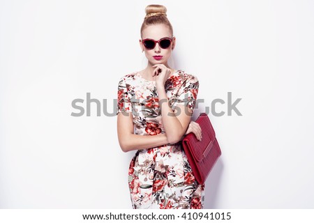 beautiful young blonde woman in nice spring dress, sunglasses, purse posing on white background in a studio. Fashion photo