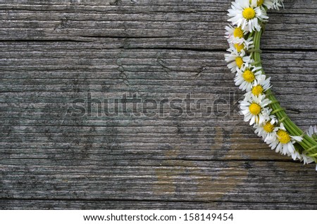 nice daisy chain on old wooden background texture