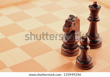 Three Wooden Chess Pieces on a Chessboard