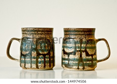 Israeli ceramic pair in green and brown tones: two mugs of 1950-th years with abstract glazed images.Symbolizes couple: He and She; brother and sister etc. Isolated on white.