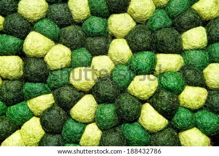 Closeup of decorative abstract carpet texture with colorful bright beads of synthetic fibers. Green tones. Useful for background.