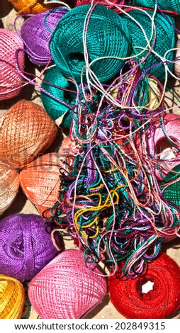 Close up: group of multi-colored tangles of thread on flea market table. Good for background.