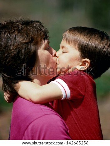 Mother and young son hugging and kissing.