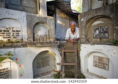 BACOLOD CITY, PHILIPPINES - MARCH 2, 2012 - An elderly, homeless Filipino man lives among stacked, concrete cemetery crypts on March 2, 2012 in Bacolod City, Philippines.