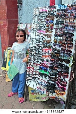 PHILIPPINES - JULY 15, 2011 - Unidentified six year old girl sells sunglasses from the sidewalk on July 15, 2011 at Philippines. The government is pushing programs to reduce child labor before 2015.