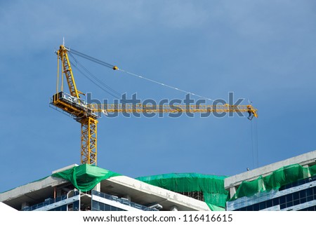 Yellow cranes on the top of building construction site against blue sky