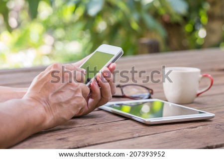 Man hands touching smart phone with green tree background