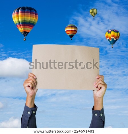 Hands holding banner with hot air balloon and blue sky background