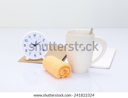 Coffee cup and orange roll cake with office accessories background