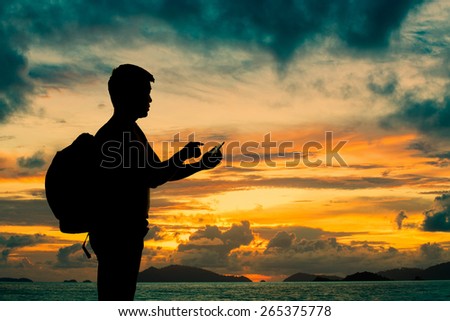 Silhouette man with smartphone in hands at sunset beach