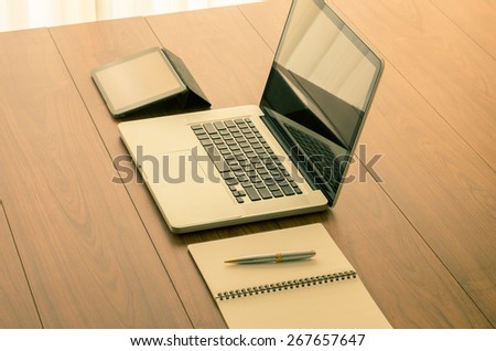 Laptop computer and office accessories on wooden table with vintage color effect