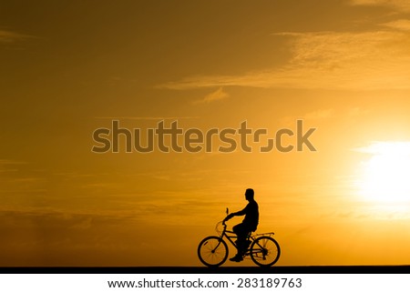 Silhouette man riding the bike at sunset