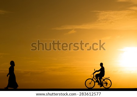 Silhouette man riding the bike at sunset