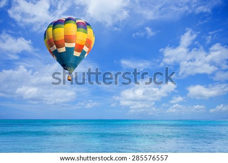 Hot air balloon fly over the sea with clouds blue sky background