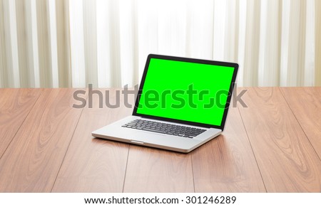 Green screen laptop computer on wooden table