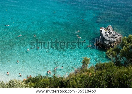 many bathers swim inside water like crystal of Mylopotamos, Greece