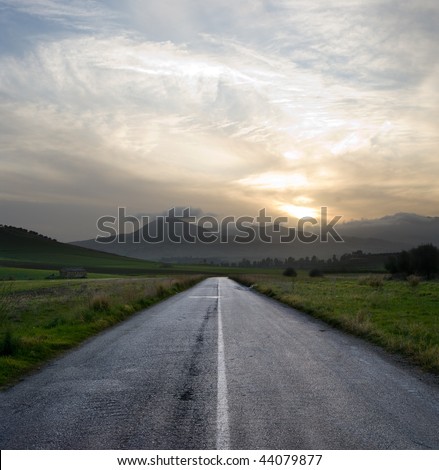 straight road crosses a desolate country road at the gloomy sunset