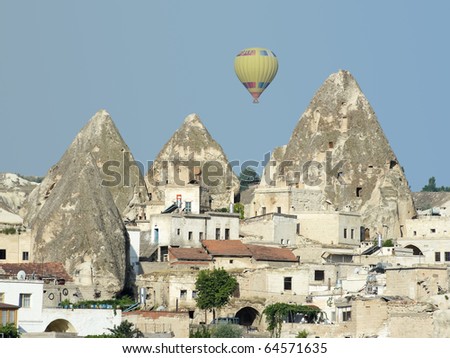 a hot air balloon over the fairy chimneys and houses in village Goreme, Cappadocia, Turkey